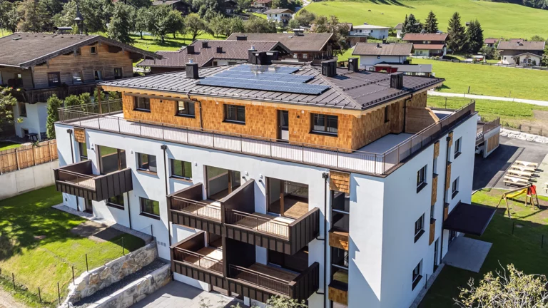 Vogelperspektive der Wohnanlage in Niedernsill mit Sicht auf die Holzschindelfassade und Photovoltaikanlage am Dach