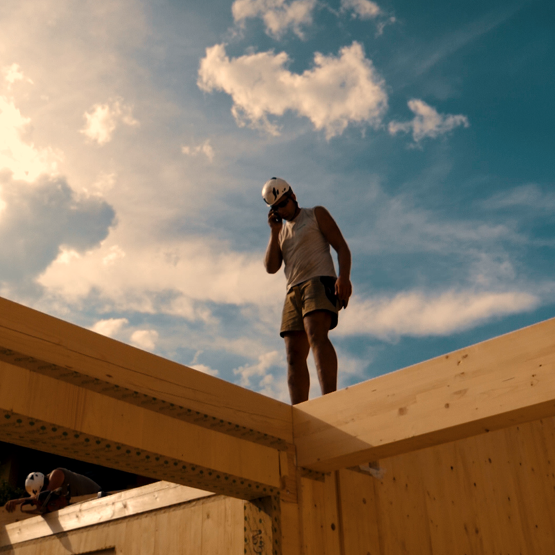 Mitarbeiter auf Balken eines Massivholzhauses