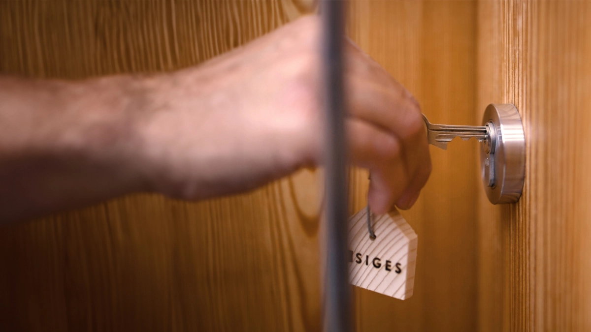 Person die einen Wohnungsschlüssel in die Wohnungstür steckt