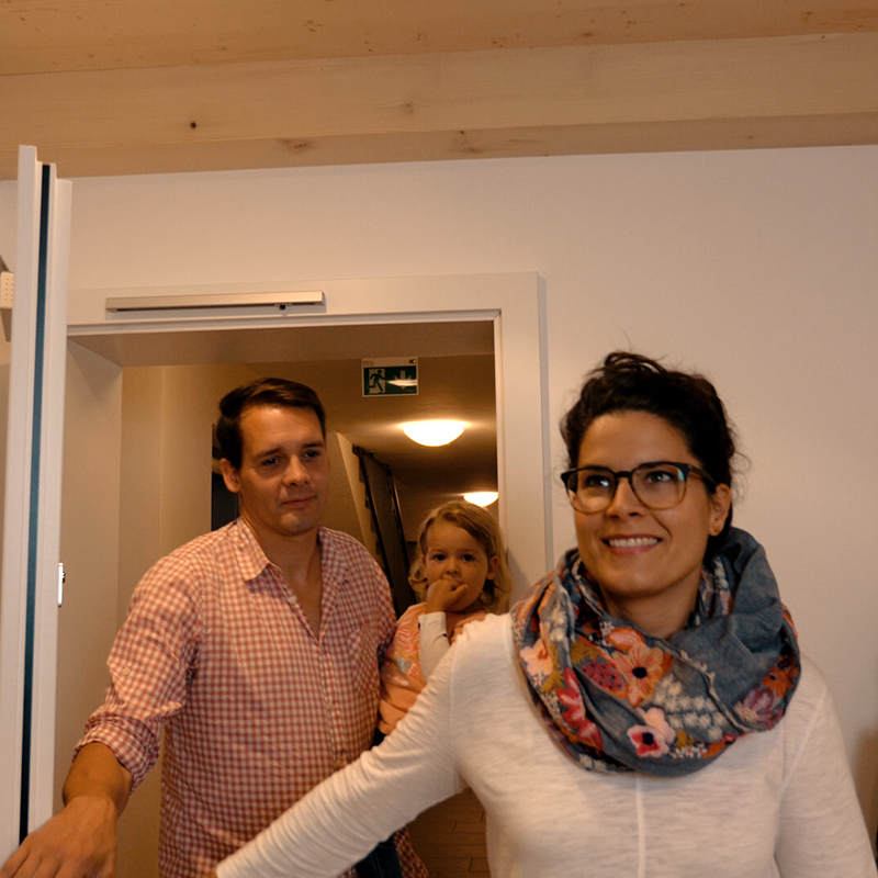 Familie betritt Wohnung mit Kleinkind auf dem Arm